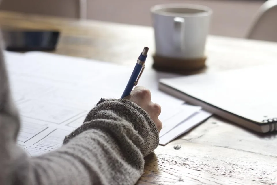 A quiet desk with a notebook and coffee in morning light
