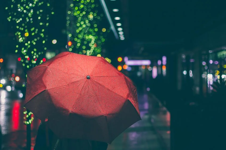 An umbrella held open against rain on a city street